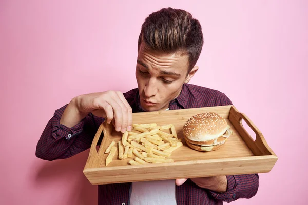 Mann mit Fast Food essen Hamburger Pommes rosa Hintergrund — Stockfoto