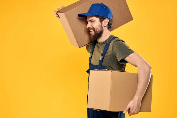 Um homem em uma forma de trabalho uma caixa com ferramentas de carregamento fundo amarelo — Fotografia de Stock