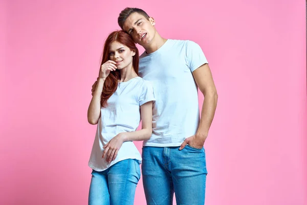 Коханці чоловік і жінка в джинсах і футболці на рожевому тлі обрізаний вид сімейний роман підлітків — стокове фото