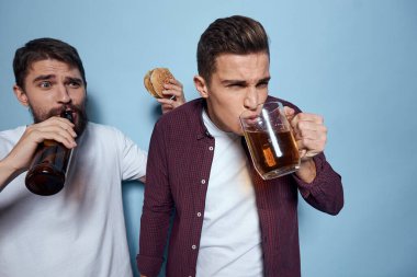 İki neşeli sarhoş arkadaş mavi bir arka planda bira içiyorlar.