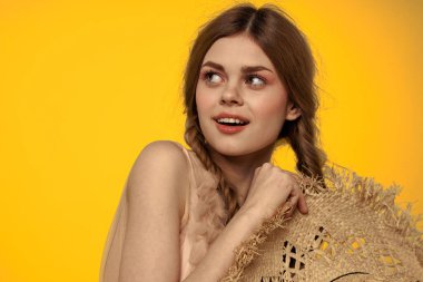 Sarı arkaplan duygularıyla elinde hasır şapkalı bir kadın... 