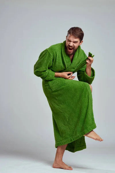 Hombre emocional en una túnica verde en un fondo de luz en pleno crecimiento divertido emociones modelo — Foto de Stock