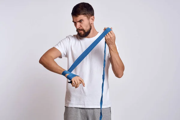 Homem de esportes em branco t-shirt azul bandagens de boxe em seus exercícios de treino de braços — Fotografia de Stock