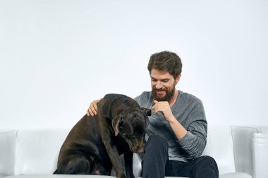 Kanepede evcil köpeği olan bir adam. Arkadaşlarıyla eğleniyor.