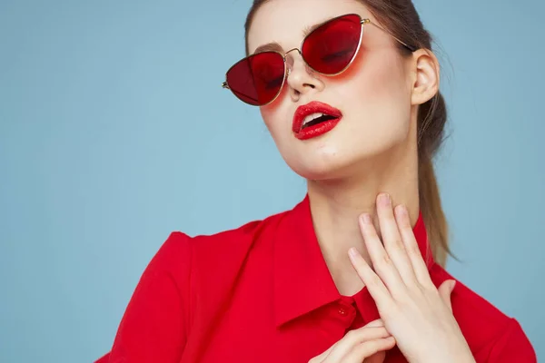 Vacker kvinna i mörka glasögon röd skjorta ljus makeup känslor attraktiv ser blå bakgrund — Stockfoto
