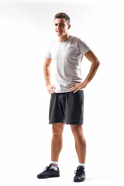 Hombre atlético sobre un fondo claro en pleno crecimiento y jogging pantalones cortos de carga zapatillas camiseta — Foto de Stock