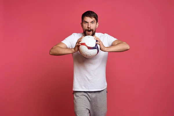 Uomo con un pallone da calcio su sfondo rosa energia gesticolare con le mani allenatore emozioni modello — Foto Stock