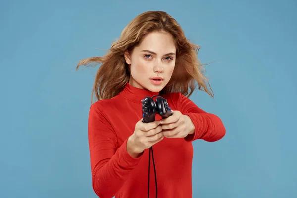 Mujer sosteniendo en sus manos dos controladores de juego entretenimiento estilo de vida chaqueta roja fondo azul — Foto de Stock