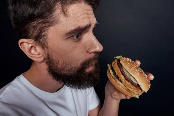 Muž jíst hamburger fast food restaurace Gourmet jíst tmavé pozadí — Stock fotografie