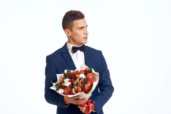 Een elegante man in een klassiek pak met een strikje houdt een boeket bloemen in zijn hand — Stockfoto