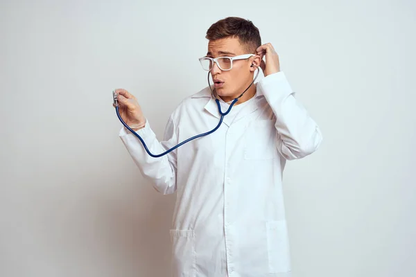 Γιατρός σε ένα ιατρικό φόρεμα με στηθοσκόπιο και γυαλιά σε ένα ελαφρύ φόντο περικοπεί πορτρέτο άποψη — Φωτογραφία Αρχείου