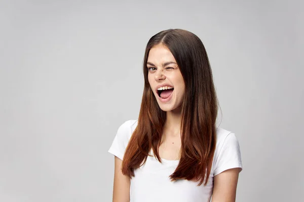 Femme émotionnelle clin d'oeil elle sur un fond clair dans un T-shirt blanc — Photo