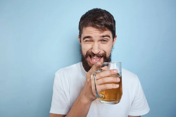 Homme joyeux dans un T-shirt blanc avec une tasse de bière fond bleu ivre — Photo