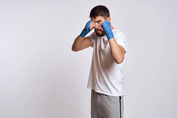 Uomo sportivo in t-shirt bianca blu bendaggi da boxe sulle braccia esercizi di allenamento — Foto Stock