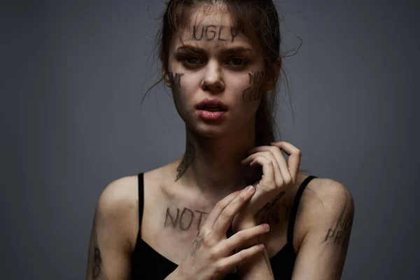 Aufgebrachte Frau mit beleidigendem Schriftzug auf ihrem Körper auf grauem Hintergrund, die sich mit abgeschnittenen Händen berührt — Stockfoto
