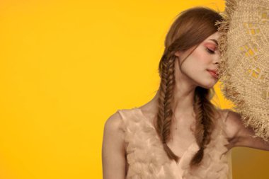 Sarı arkaplan duygularıyla elinde hasır şapkalı bir kadın... 