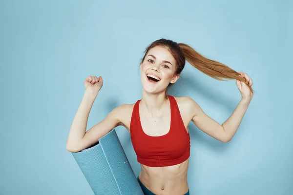 Esterilla de entrenamiento de mujer deportiva en las manos Red Tank Top ejercicio fondo azul —  Fotos de Stock