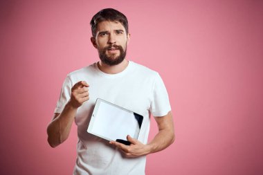 Adam pembe arkaplan kodları üzerinde bir tablet reklamını yapıyor. Duyguların beyaz t-shirt modeli yeni teknolojiler görüntüsünü kırpıyor.
