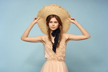 Mavi arka planda pembe elbiseli bir kız elleriyle romantik modeller yapıyor.