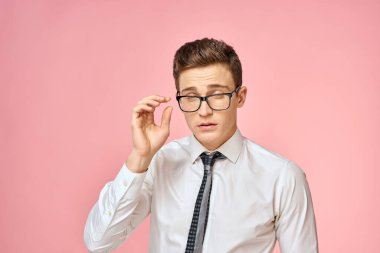 Beyaz gömlekli, kravatlı, gözlüklü, kendine güvenen, resmi pembe arka planlı bir iş adamı.