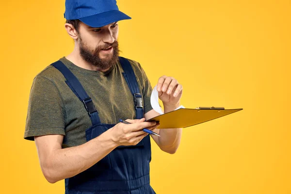 Mann in Arbeitsform dokumentiert Transport-Lieferservice gelben Hintergrund — Stockfoto