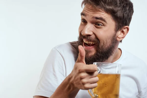Чоловік з чашкою пива в руках і білою футболкою світлий фон вуса борода модель емоцій — стокове фото