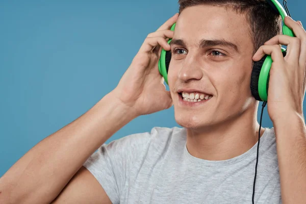 Man i gröna hörlurar lyssnar på musik underhållning livsstil vit t-shirt blå bakgrund — Stockfoto