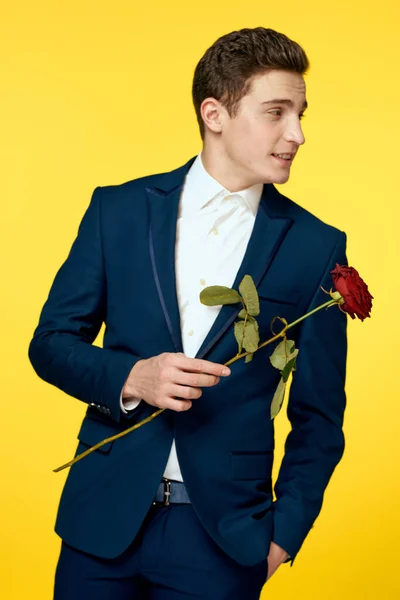 Gentleman im klassischen Anzug auf gelbem Hintergrund mit roter Rosenromantik — Stockfoto