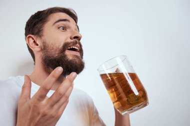 Büyük bir bardak birayla duygusal bir adam alkollü içki içiyor ve sarhoş halde el kol hareketi yapıyor.