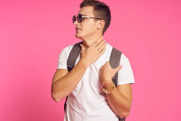 Mann mit Sonnenbrille und Rucksack weißes T-Shirt Jugendstil rosa Hintergrund — Stockfoto