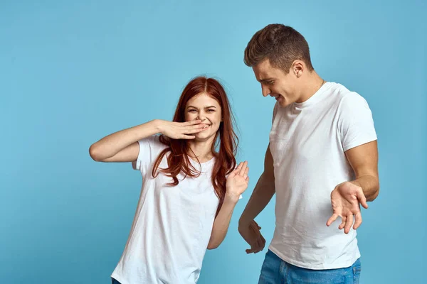 Homem e mulher apaixonados em jeans e uma camiseta em um fundo azul abraçar uns aos outros e se divertir — Fotografia de Stock