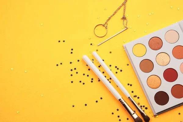 Eyeshadows and makeup brushes on a yellow background top view professional cosmetics — Stock Photo, Image