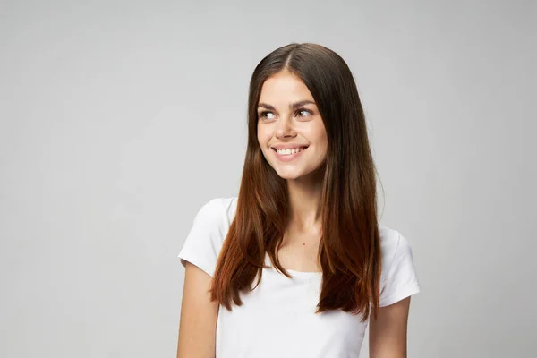 Happy brunetka kobieta patrzy na bok na lekkim tle biały t-shirt — Zdjęcie stockowe