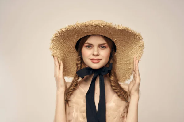 Мила дівчина в солом'яному капелюсі з чорною стрічкою і сукня на бежевому фоні обрізаний вид — стокове фото