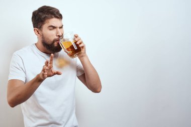 Elinde bir kupa bira ve beyaz tişörtlü açık renk bıyıklı sakallı bir adam.