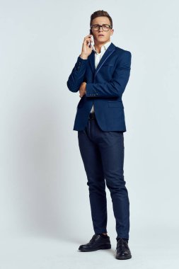 Takım elbiseli bir iş adamı telefonda konuşuyor. Stüdyonun ışık arka planında.