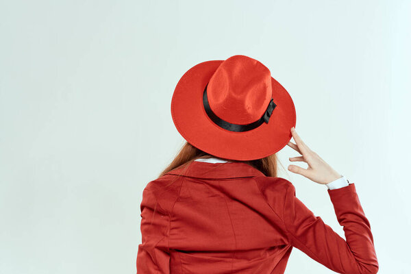 Woman in red hat and jacket back view elegant style light background