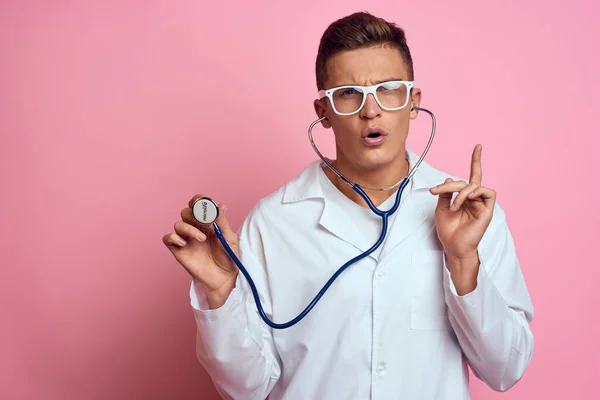 Young doctor with a stethoscope and glasses on a pink background nurse interns model — Stock Photo, Image