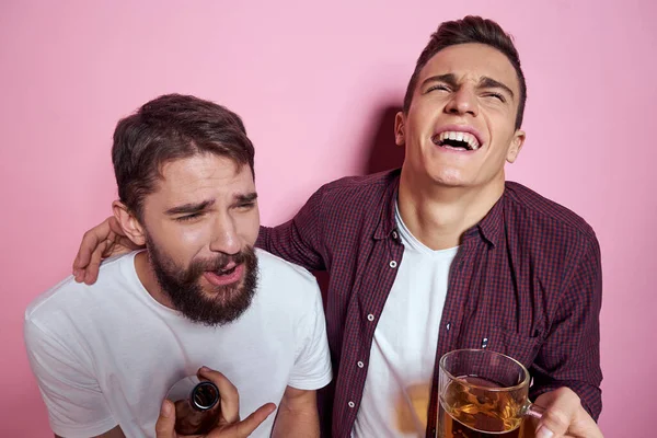 Двое мужчин пьют пиво дружба пьяный алкоголь образ жизни розовый фон — стоковое фото