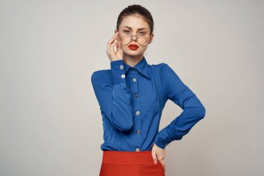 Mavi gömlekli ve kırmızı gözlüklü kadın model. Güzel yüz makyajı stüdyosu.