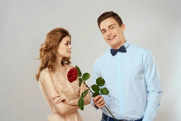 Szerelmesek férfiak és nő ölelés romantika szerelem piros rózsa fény háttér — Stock Fotó
