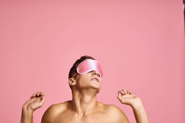 Pembe uyku maskeli bir adam pembe arka planda çıplak omuzlarında sabah