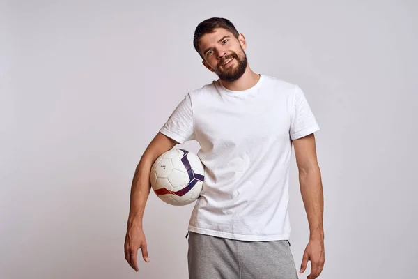 Allenatore maschile con un pallone da calcio in mano su uno sfondo leggero spiegazione energetica dei movimenti — Foto Stock