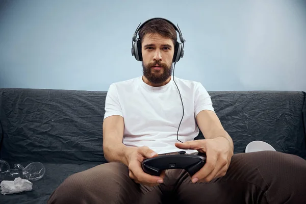 Man zittend op de bank met een koptelefoon en gamepad spelend in de levensstijl van de voedselvrije tijd — Stockfoto