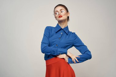 Mavi gömlekli ve kırmızı gözlüklü kadın model. Güzel yüz makyajı stüdyosu.