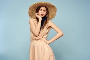 Mavi arka planda pembe elbiseli bir kız elleriyle romantik modeller yapıyor.