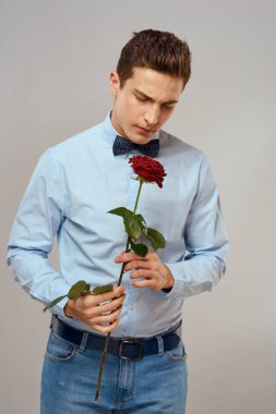 Kırmızı güllü ve açık renk gömlekli yakışıklı bir adamın portresi.