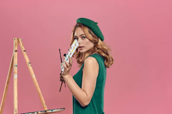 Kvinna konstnär grön basker akvarell borste teckning konst färg livsstil hobby rosa bakgrund — Stockfoto