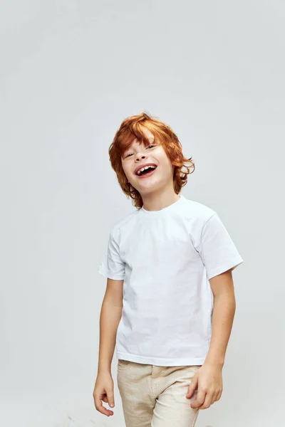 Imbir chłopiec szeroki uśmiech biały t-shirt studio szary tło — Zdjęcie stockowe