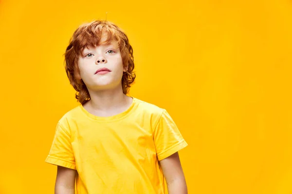 黄色のTシャツに興味のある顔の表情で赤い髪の子供の前のビュー — ストック写真